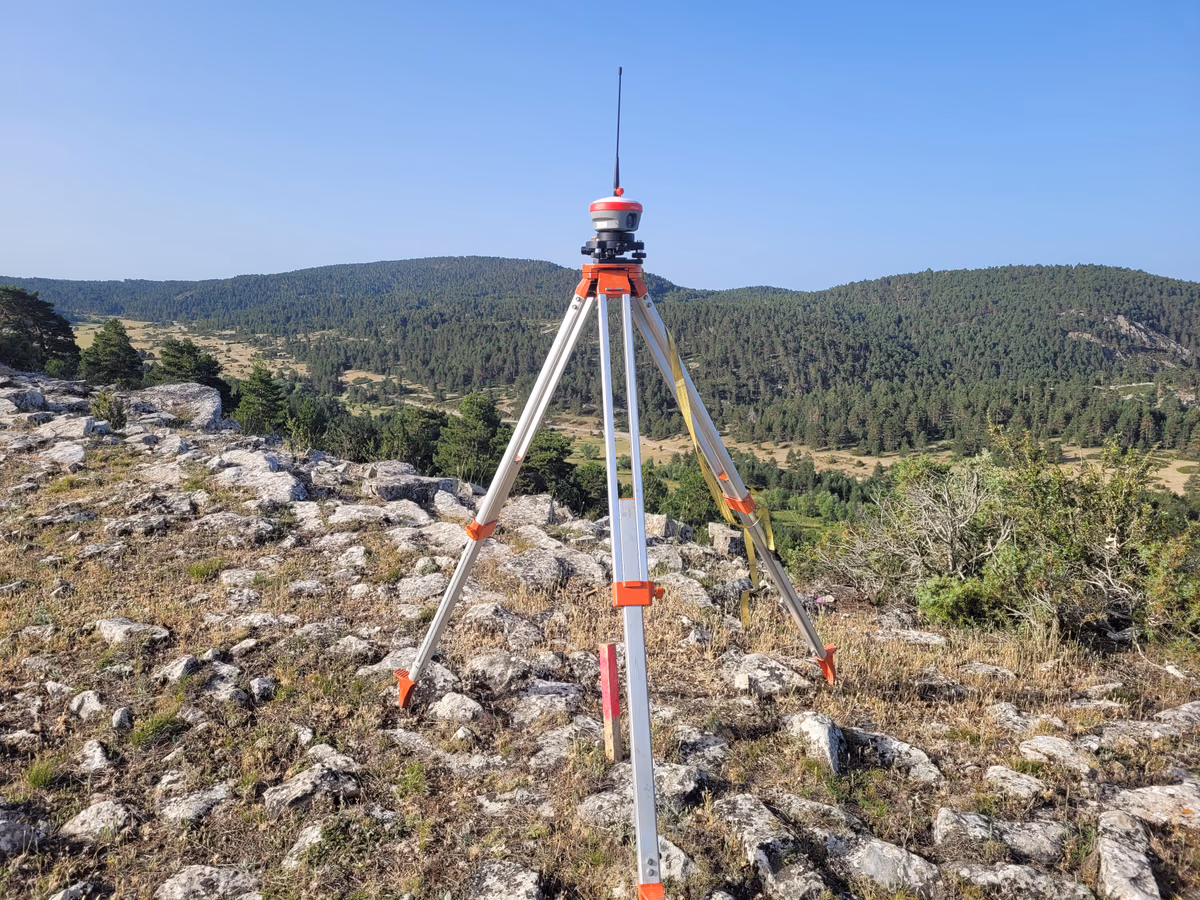 Receptor GNSS de precisión instalado sobre un trípode en un paisaje forestal